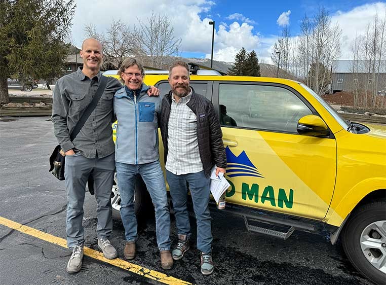 Company staff posing for a photo next to the company vehicle